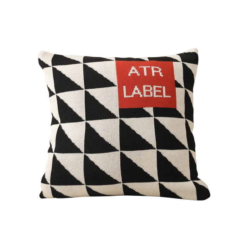 Geometrisches Strickkissen mit Dreiecksmuster und Logo-Patch