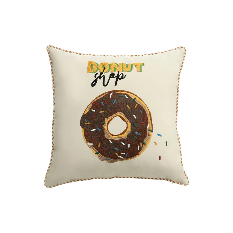 Quadratisches Dekokissen mit gesticktem Donut-Motiv und dekorativer Kederkante