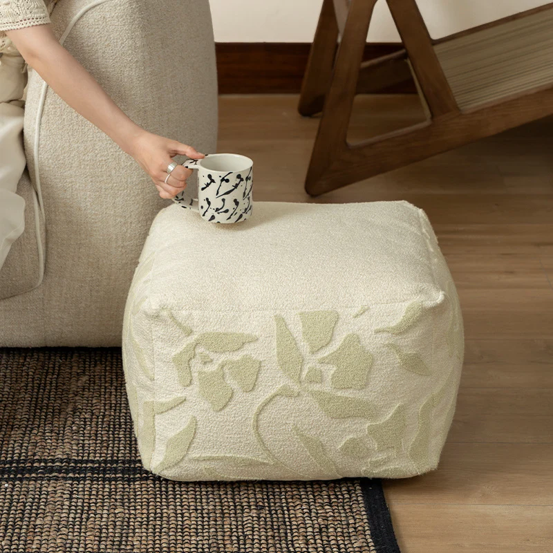 Quadratischer Bodensitzpouf mit strukturierter Bouclé‑Oberfläche und floralem Relief